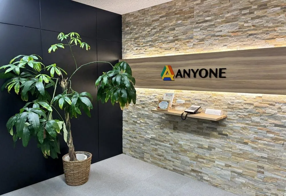 株式会社ANYONEのロゴと観葉植物のある社内エントランス